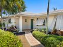 Charming entryway with a brick walkway, lush landscaping, and a bright green front door and white shutters at 1014 Contento St, Sarasota, FL 34242