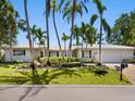 Inviting single-story home featuring manicured landscaping, a brick driveway, and mature tropical palm trees at 1014 Contento St, Sarasota, FL 34242