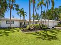 Inviting single-story home with manicured landscaping, mature tropical palm trees, and a well-kept lawn at 1014 Contento St, Sarasota, FL 34242