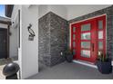 Stylish front entry features a bright red modern door with stone accents at 1116 406Th E Ct, Myakka City, FL 34251