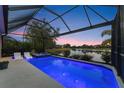 Stunning screened-in pool with a built-in spa overlooking a serene lake at sunset at 12237 Longview Lake Cir, Bradenton, FL 34211