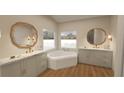 Elegant bathroom featuring dual sinks, marble countertops, decorative gold mirrors, and a soaking tub at 12535 Estrella Blvd, Punta Gorda, FL 33955