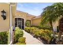 Inviting front entrance featuring a screened porch, tiled walkway, and colorful, manicured landscaping at 27243 Ipswich Dr, Englewood, FL 34223
