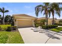 Inviting single-story home showcasing a spacious driveway, two-car garage, and lush tropical landscaping at 27243 Ipswich Dr, Englewood, FL 34223