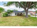 Single-story home with a lush green lawn and mature shade tree at 4415 Charing Cross Rd, Sarasota, FL 34241