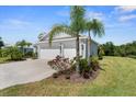Side exterior view of the home featuring lush landscaping, mature palm trees, and a well-maintained lawn at 4515 Roycroft Ter, Parrish, FL 34219