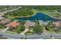 Aerial view of a home with a clay tile roof, pool, lake, and golf course views at 6633 The Masters Ave, Lakewood Ranch, FL 34202