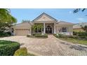 Charming home with a clay tile roof, arched entryway, brick driveway, and attached garage at 6633 The Masters Ave, Lakewood Ranch, FL 34202