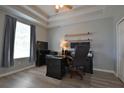 Cozy bedroom with wood-look floors, tray ceiling, and neutral paint at 8121 Snowy Egret Pl, Bradenton, FL 34202