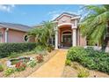Charming front entrance with double doors, a water feature, and lush, tropical landscaping at 9915 Old Hyde Park Pl, Bradenton, FL 34202