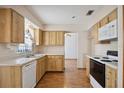 Bright kitchen featuring wood cabinets, white appliances, and durable laminate flooring at 1007 Southern Pine Ln, Sarasota, FL 34243