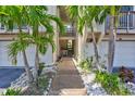 Inviting condo entrance framed by lush palms, leading to a private stairway and attached garage, showcasing beach living at 1155 Lake House Cir # C119, Sarasota, FL 34242