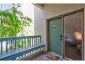 Charming condo entrance features a teal door with a welcome mat, complemented by a cozy bench and leafy plants at 1155 Lake House Cir # C119, Sarasota, FL 34242