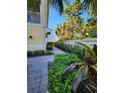 Exterior side view of a well-landscaped property with a walkway and mature plants and shrubs at 116 Navigation Cir # 106, Osprey, FL 34229