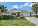 Charming single-story home featuring a well-manicured lawn, lush landscaping, and a welcoming two-car garage at 12133 Forest Park Cir, Bradenton, FL 34211
