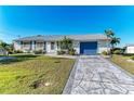 A single-story home with a decorative driveway, manicured lawn, and a vibrant blue garage door at 18082 Eau Gallie S Cir, Port Charlotte, FL 33948