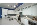 Modern kitchen featuring white cabinets, stainless steel appliances, and stylish backsplash and light blue wall at 212 Spring Ave, Anna Maria, FL 34216