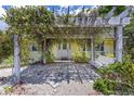 Inviting front entrance with a vine-covered pergola and cozy bench seating at 2165 Lemon Ave, Englewood, FL 34223
