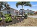 Charming home featuring an American flag, stone accents, mature palms, and a lush, landscaped front yard at 238 Lookout Point Dr, Osprey, FL 34229