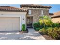 Close-up exterior showcases a tile roof, stone accents, a two-car garage and lush landscaping at 2525 Vaccaro Dr, Sarasota, FL 34231