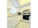 The kitchen is equipped with white cabinetry and includes a microwave, range, and a window for natural light at 3559 Lake Bayshore Dr # J-204, Bradenton, FL 34205