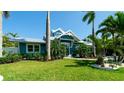 Charming blue home boasts lush landscaping and a well-manicured lawn, creating a welcoming curb appeal at 403 75Th St, Holmes Beach, FL 34217