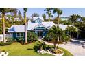 Charming blue home boasts lush landscaping and a well-manicured lawn, creating a welcoming curb appeal at 403 75Th St, Holmes Beach, FL 34217