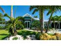 Charming blue home boasts lush landscaping and a well-manicured lawn, creating a welcoming curb appeal at 403 75Th St, Holmes Beach, FL 34217