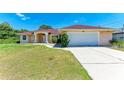 Home exterior featuring a two-car garage, well-manicured lawn and walkway leading to the front door at 5168 Cillette Ave, North Port, FL 34288