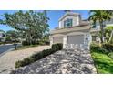 Spacious three-car garage with a paver driveway, set against a backdrop of well-maintained landscaping and trees at 5283 Descanso Ct # 101B18, Sarasota, FL 34238