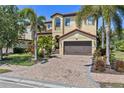 Stately two-story home with a brick driveway, lush landscaping and mature palm trees at 5503 Title Row Dr, Bradenton, FL 34210