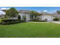 Well-maintained single-story home with lush green lawn, garden beds, and a two-car garage at 5782 Sandy Pointe Dr, Sarasota, FL 34233