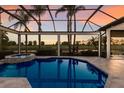 Screened pool area features a spa with golf course and water views at sunset at 7218 Teal Creek Gln, Lakewood Ranch, FL 34202