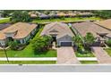 Aerial view of a home with a tile roof, surrounded by a lush green lawn, palm trees, and neighboring houses at 8713 Mangilli Rd, Sarasota, FL 34238