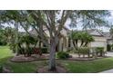 Inviting single-story house showcases manicured lawn, mature trees, and a welcoming front entrance with landscaping at 11592 57Th Street E Cir, Parrish, FL 34219