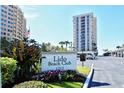 Exterior of the Lido Beach Club featuring a sign, lush landscaping, and a well-maintained parking area at 1212 Benjamin Franklin Dr # 503, Sarasota, FL 34236