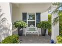 Inviting front porch with a white bench flanked by decorative potted plants and a window with blue shutters above at 12706 Cobalt Ter, Bradenton, FL 34211