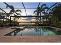 Sparkling screened-in pool and spa with a tranquil lake view at sunset at 16309 Castle Park Ter, Lakewood Ranch, FL 34202