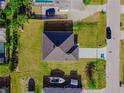 Aerial perspective of a home with a dark gray roof and vibrant green lawn, showcasing its location at 18182 Steele Ave, Port Charlotte, FL 33948