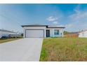 Bright single-story home with a two-car garage, modern front door, and manicured lawn under a clear sky at 18182 Steele Ave, Port Charlotte, FL 33948