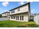 Exterior view of the home revealing a manicured lawn, white fence, and a set of French doors for backyard access at 3111 W Nassau St, Tampa, FL 33607