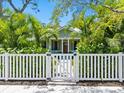 Charming home featuring a gated white picket fence and lush tropical landscaping at 324 Julia Pl, Sarasota, FL 34236