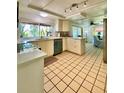 Bright kitchen featuring white cabinets, light countertops, tile floors, and a view into the living space at 3325 Honeymoon Ln, Holiday, FL 34691