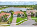 Stunning lakefront home with lush landscaping, a red tile roof, and a paver driveway at 5923 Snowy Egret Dr, Sarasota, FL 34238