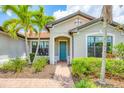 Charming home entrance with a vibrant blue door, lush landscaping, and a brick walkway at 5923 Snowy Egret Dr, Sarasota, FL 34238