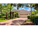 Beautiful single-story home featuring a red brick driveway, beige siding, and lush landscaping with a two-car garage at 6924 Cumberland Ter, University Park, FL 34201