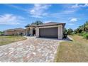 Single-story home with an arched entrance, two-car garage, and a colorful brick driveway at 8123 Wawana Rd, North Port, FL 34287