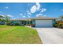 Desirable single-Gathering home with lush landscaping, mature trees, and a large driveway leading to an attached two-car garage at 9321 New Martinsville Ave, Englewood, FL 34224