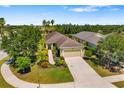 Landscaped single-story home with driveway, surrounded by mature trees and lush greenery under a clear blue sky at 11634 Piedmont Park Xing, Bradenton, FL 34211