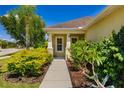 Inviting front porch surrounded by lush landscaping with mature trees and flowering shrubs at 11634 Piedmont Park Xing, Bradenton, FL 34211
